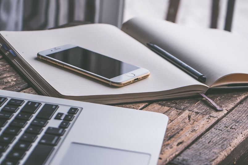 iPhone on top of a notebook beside a MacBook