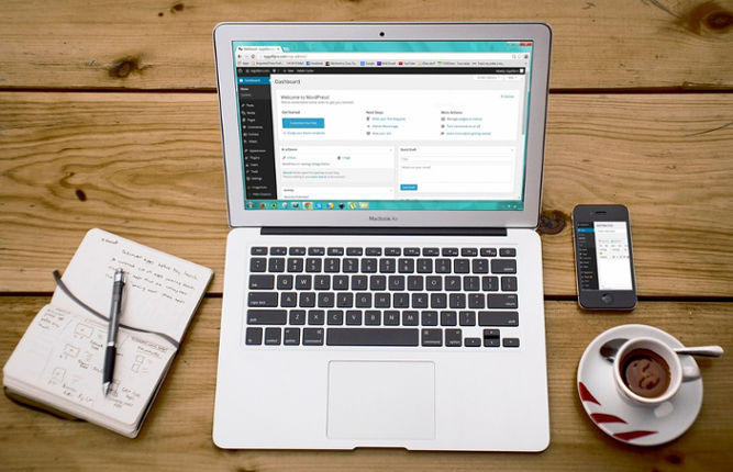 MacBook Air, cup of coffee, and a notebook